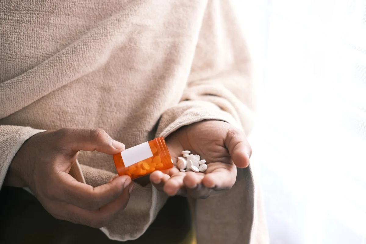 addiction treatment programs covered by insurance - man's hand with pills spilled out of the container .