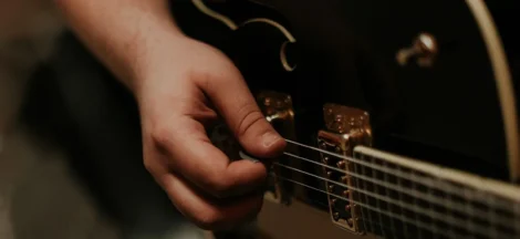guitar chords for popular songs - A person picks an electric guitar